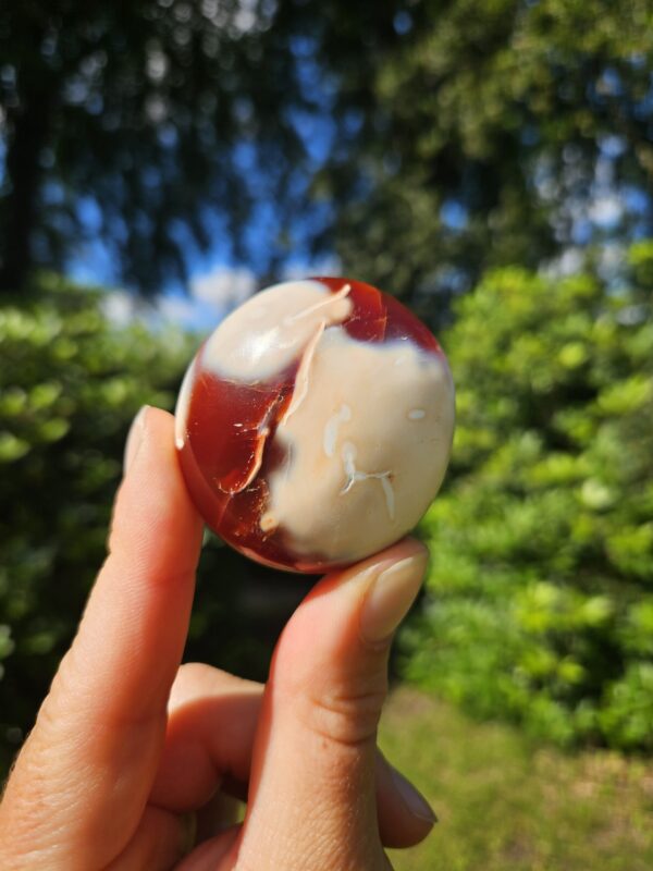 Karneol palmstone i varme, orange og røde nuancer. Denne krystal er kendt for at styrke mod, energi og kreativitet. Den hjælper med at aktivere livskraften, fremme selvværd og skabe balance i kroppens energiflow.