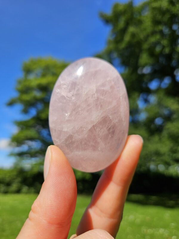 Rosakvarts palmstone, med bløde, lyserøde nuancer, kendt for at åbne hjertet for kærlighed, harmoni og følelsesmæssig heling.