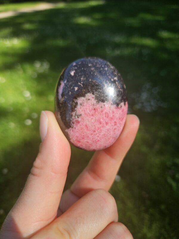 Rhodonit palmstone med smukke rosa og sorte mønstre, kendt for at fremme følelsesmæssig heling, tilgivelse og balance i relationer.