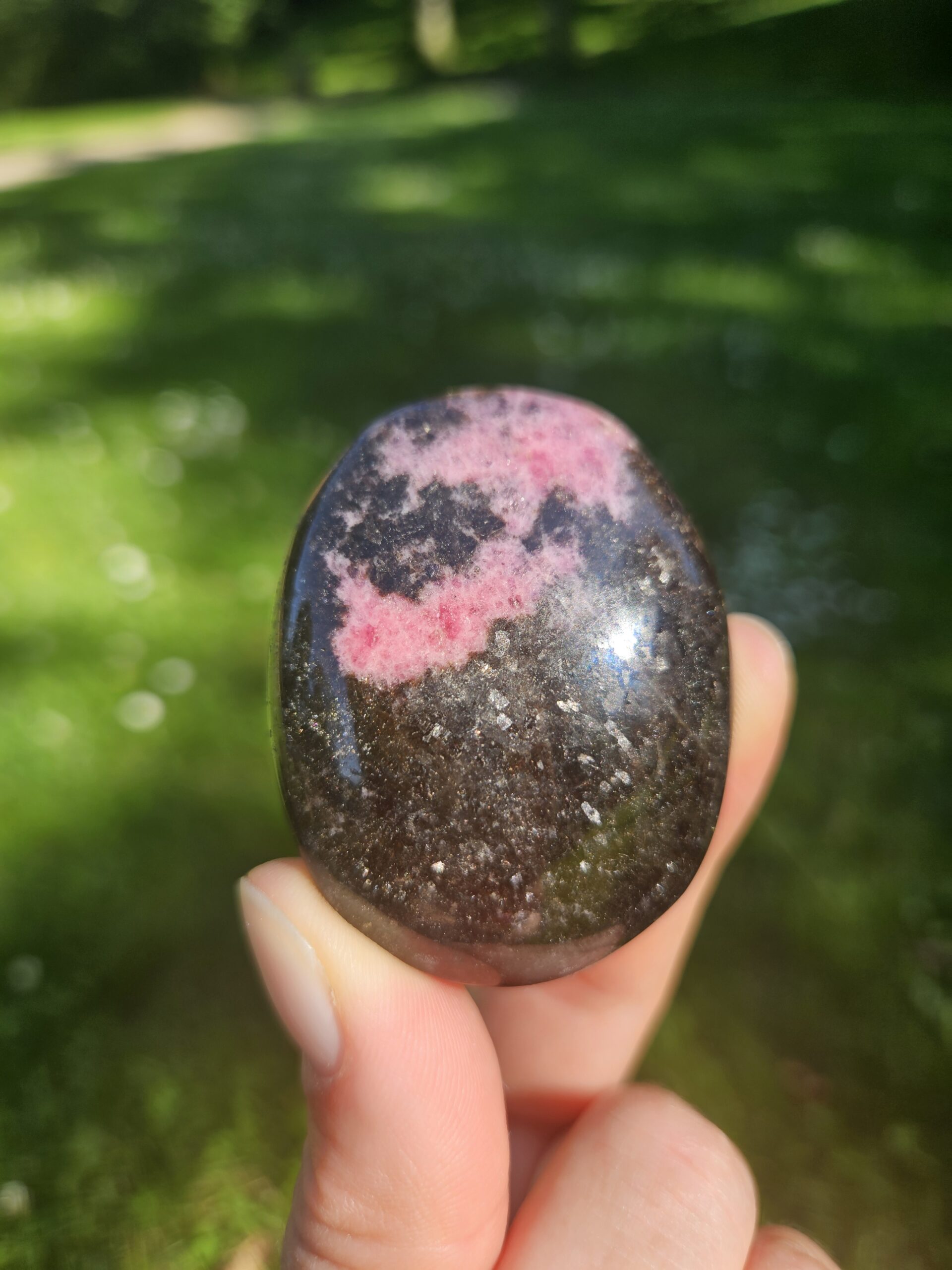 Rhodonit palmstone med smukke rosa og sorte mønstre, kendt for at fremme følelsesmæssig heling, tilgivelse og balance i relationer.