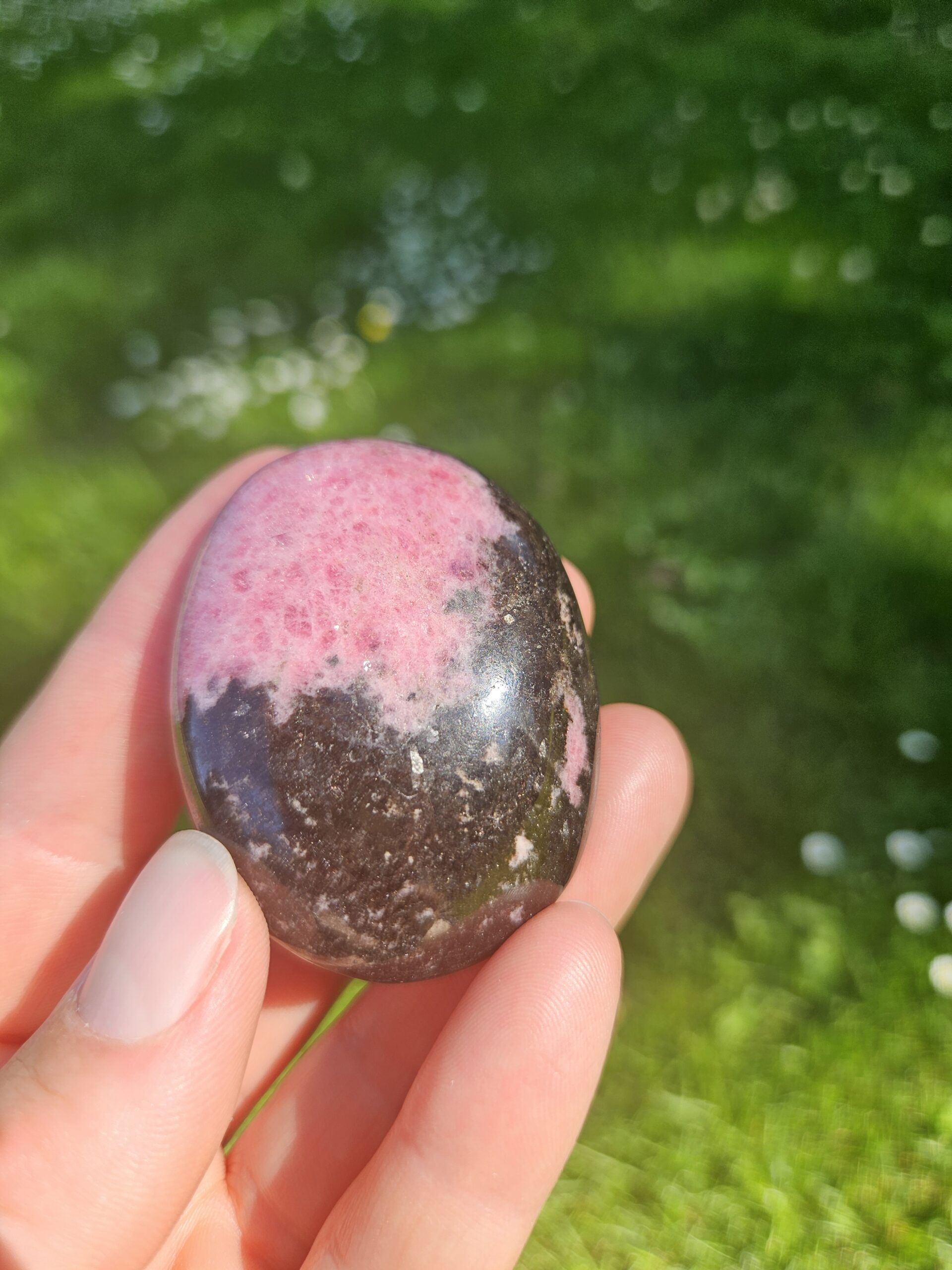 Rhodonit palmstone med smukke rosa og sorte mønstre, kendt for at fremme følelsesmæssig heling, tilgivelse og balance i relationer.