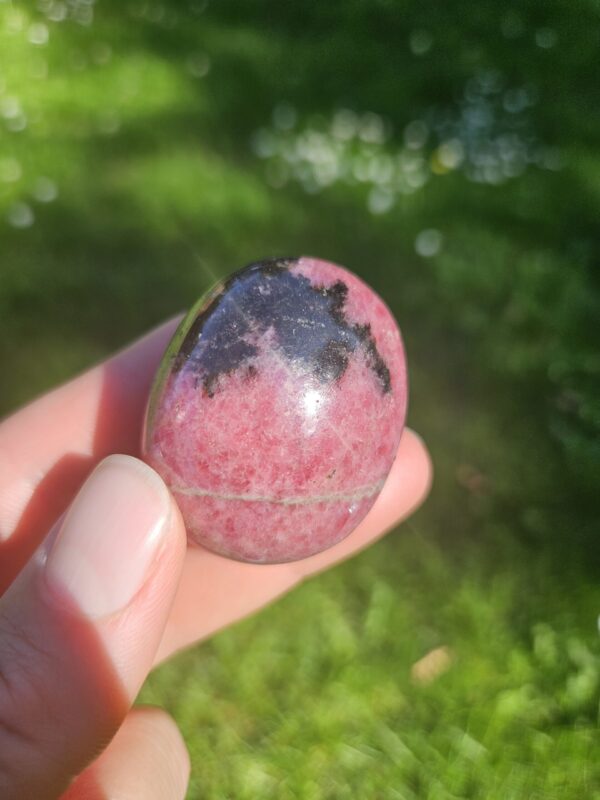 Rhodonit palmstone med smukke rosa og sorte mønstre, kendt for at fremme følelsesmæssig heling, tilgivelse og balance i relationer.