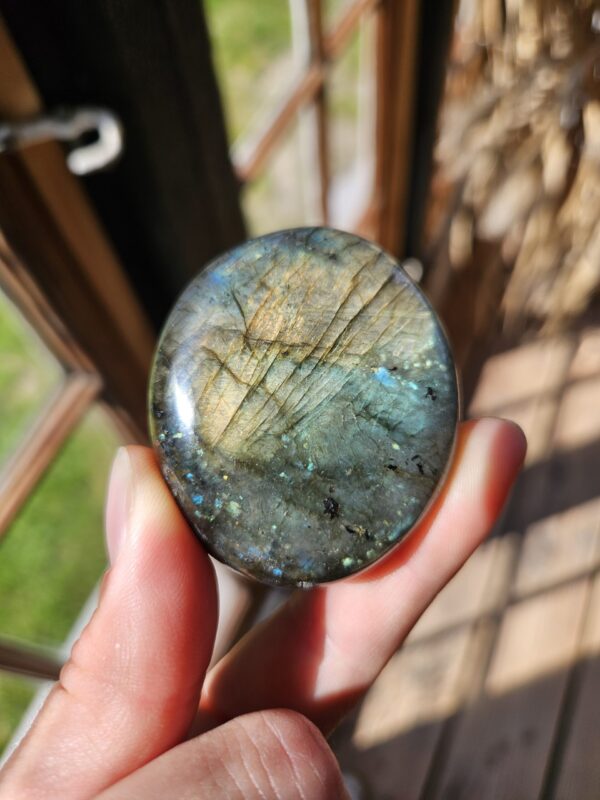 Labradorit palmstone med et fantastisk farvespil i blå, grøn og guld. Denne krystal støtter transformation, beskytter mod negativ energi og fremmer intuition samt indre ro. Den hjælper dig med at åbne sindet for nye muligheder og styrke din åndelige forbindelse.