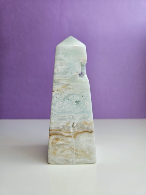 Caribisk calcit tårn med beroligende blå, hvide og beige nuancer. Denne krystal fremmer ro, balance og mental klarhed, samtidig med at den hjælper med at løsne op for følelsesmæssige blokeringer. Perfekt til at skabe et harmonisk og fredfyldt miljø.