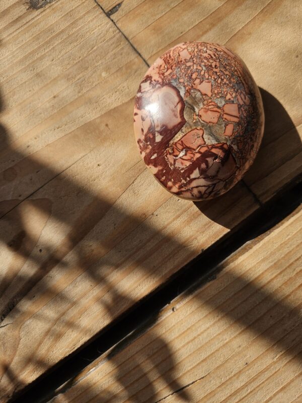 Poleret mookait palmstone, en smuk og farverig krystal, der udstråler energi af styrke og balance. Mookait siges at fremme personlig vækst, beslutsomhed og mod til at tage beslutninger, mens den samtidig bringer en følelse af ro og stabilitet. Perfekt til at have med sig i hverdagen.