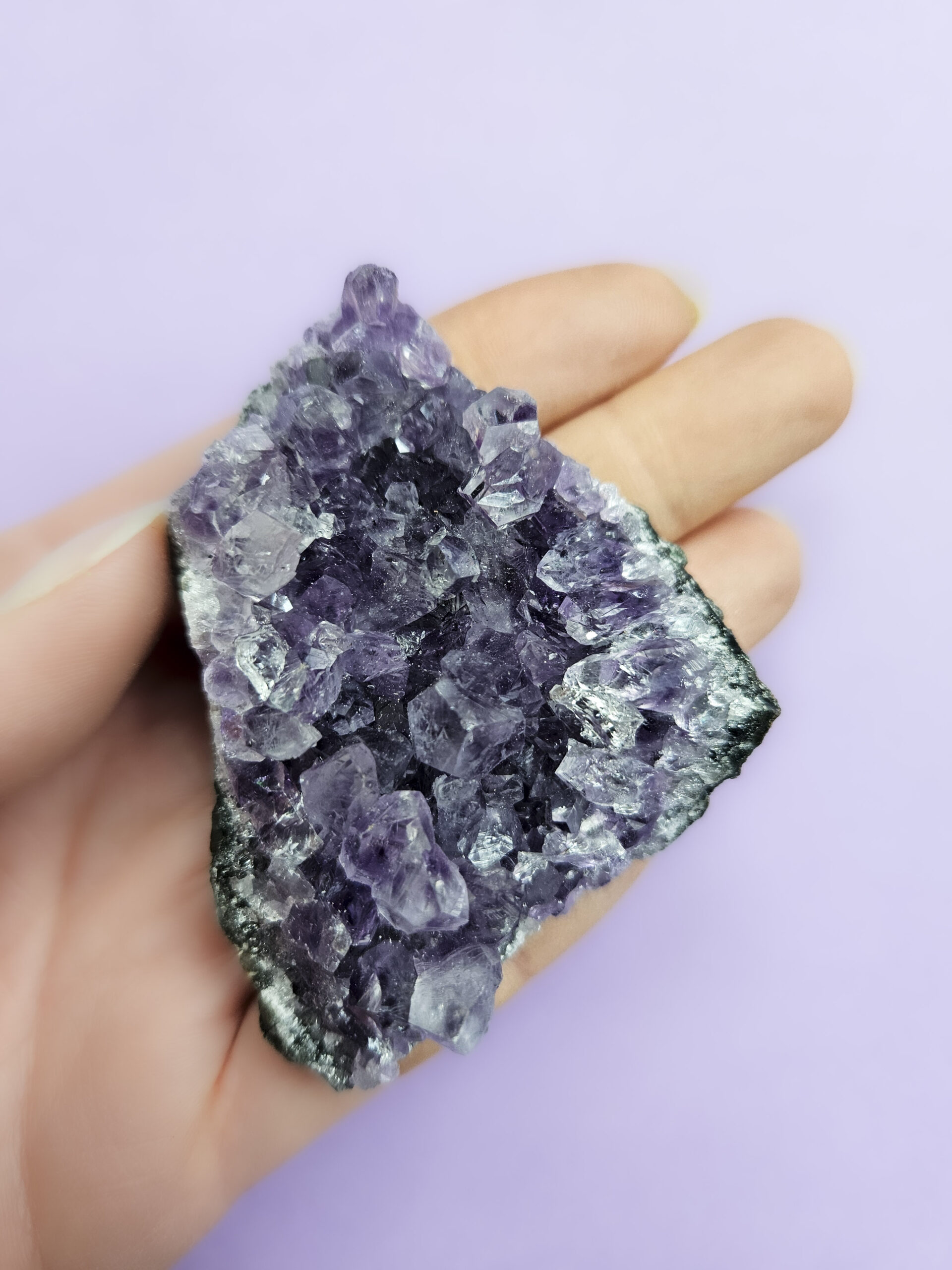 Ametyst klynge, kendt for sine beroligende egenskaber, der fremmer indre ro, åndelig vækst og beskytter mod negative energier. Glimter som en smuk violet stjernehimmel.