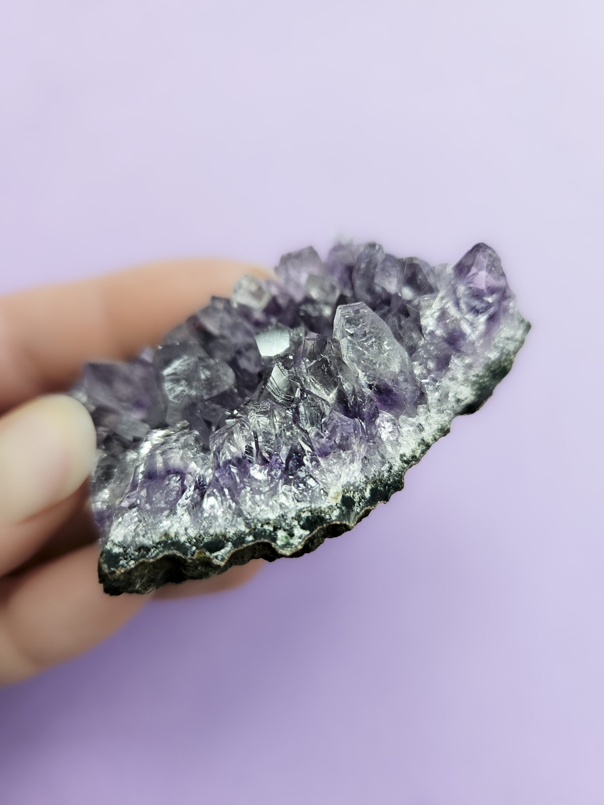 Ametyst klynge, kendt for sine beroligende egenskaber, der fremmer indre ro, åndelig vækst og beskytter mod negative energier. Glimter som en smuk violet stjernehimmel.