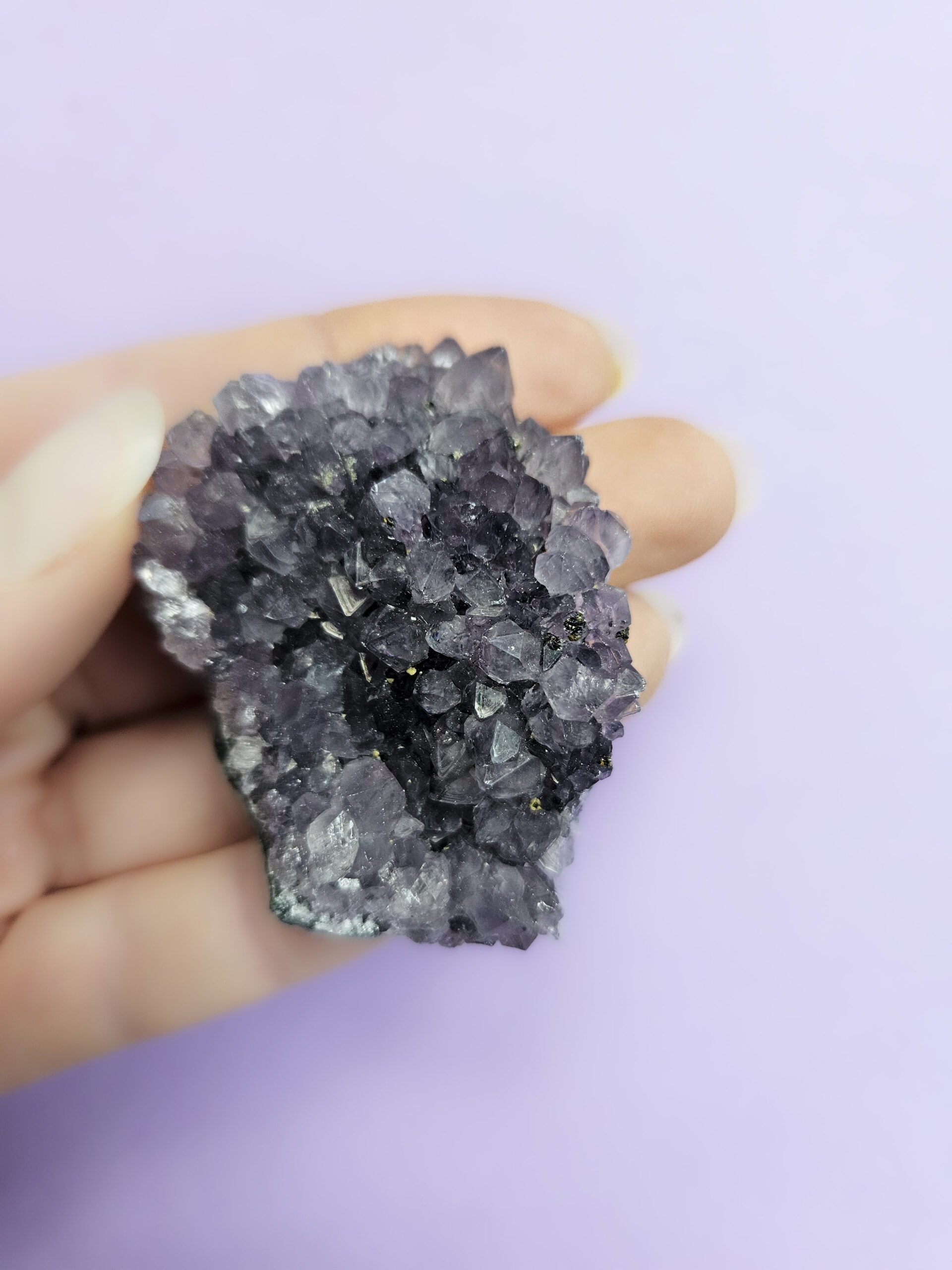 Ametyst klynge, kendt for sine beroligende egenskaber, der fremmer indre ro, åndelig vækst og beskytter mod negative energier. Glimter som en smuk violet stjernehimmel.