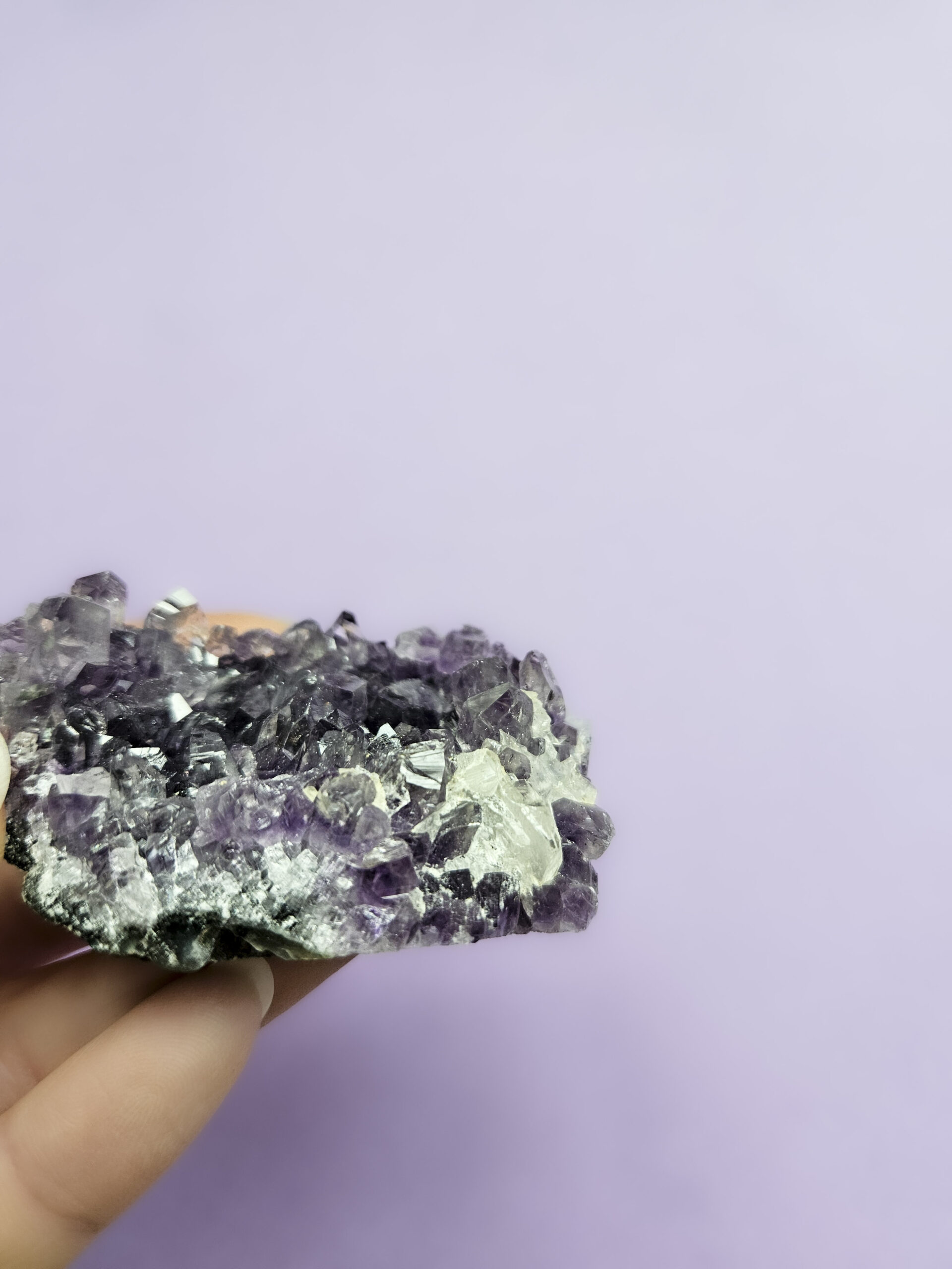 Ametyst klynge, kendt for sine beroligende egenskaber, der fremmer indre ro, åndelig vækst og beskytter mod negative energier. Glimter som en smuk violet stjernehimmel.