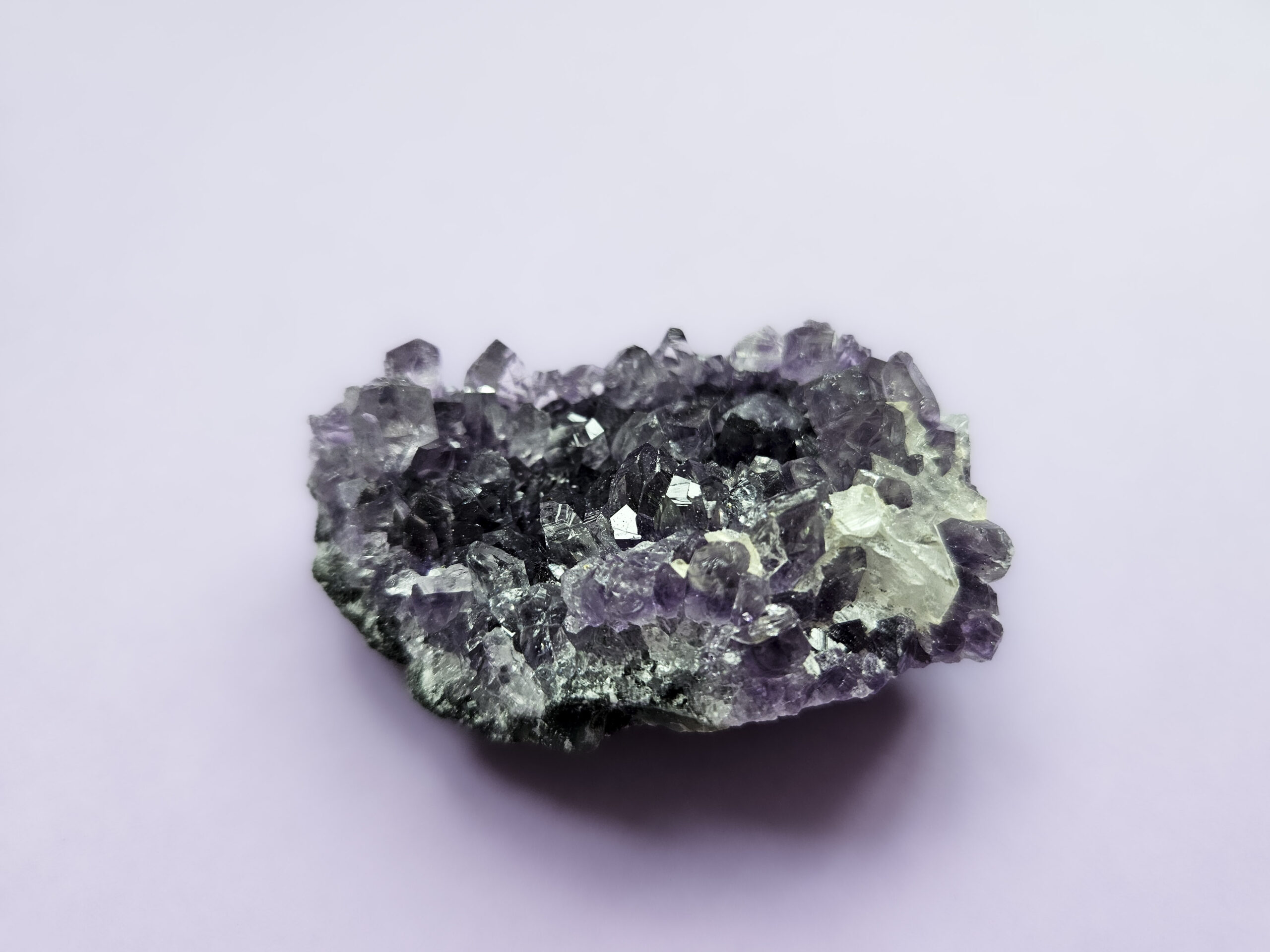 Ametyst klynge, kendt for sine beroligende egenskaber, der fremmer indre ro, åndelig vækst og beskytter mod negative energier. Glimter som en smuk violet stjernehimmel.