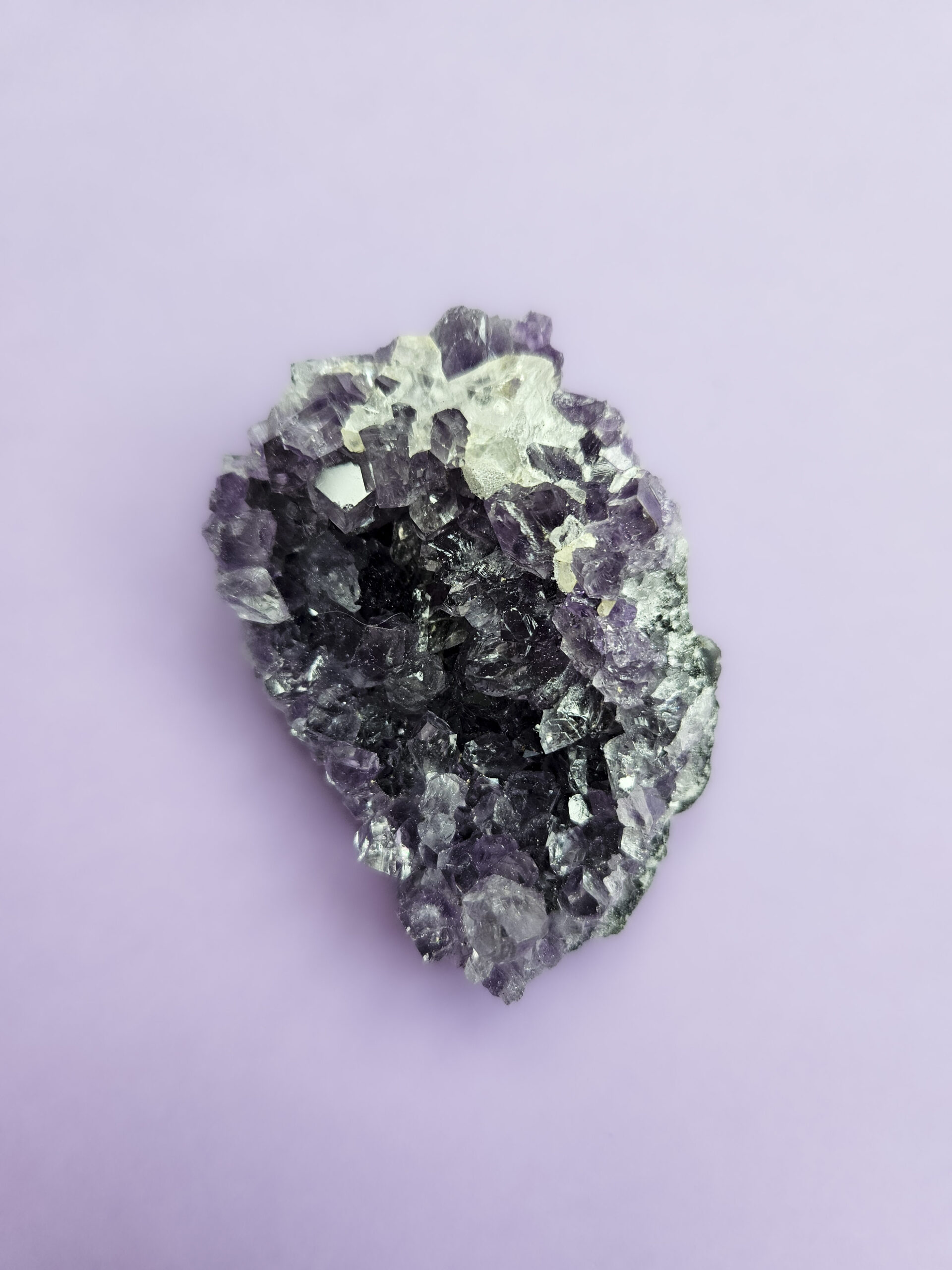 Ametyst klynge, kendt for sine beroligende egenskaber, der fremmer indre ro, åndelig vækst og beskytter mod negative energier. Glimter som en smuk violet stjernehimmel.