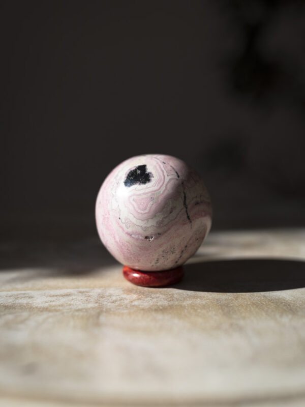 Rhodochrosit krystalkugle med bløde og dybe rosa nuancer - et symbol på kærlighed, og en støtte til selvomsorg og følelsesmæssig healing.