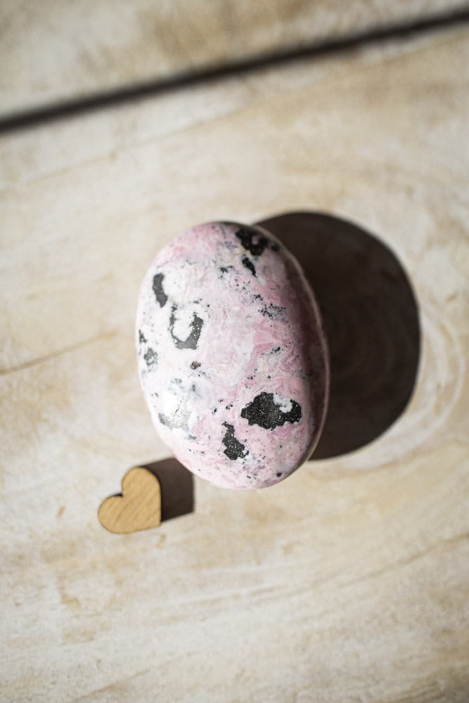 Rhodochrosit palmstone i håndpoleret kvalitet - lyserød krystal med naturlige bånd, ideel til selvkærlighed, healing og meditation.