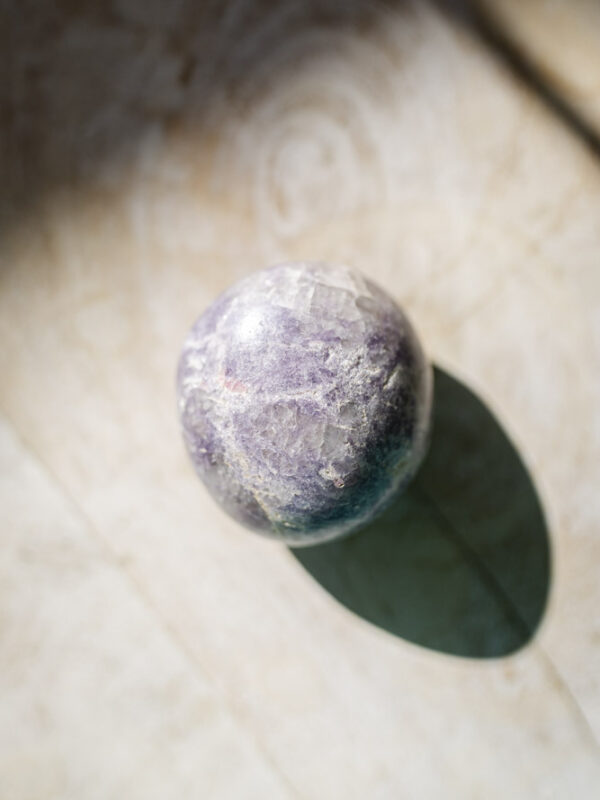 Lepidolit palmstone i lilla nuancer - kendt for beroligelse, følelsesmæssig balance og stresslindring.