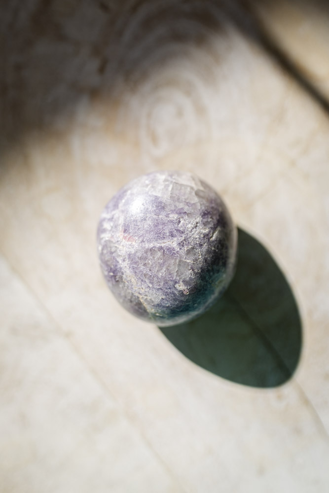 Lepidolit palmstone i lilla nuancer - kendt for beroligelse, følelsesmæssig balance og stresslindring.