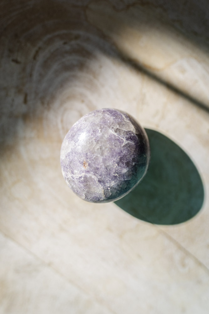 Lepidolit palmstone i lilla nuancer - kendt for beroligelse, følelsesmæssig balance og stresslindring.
