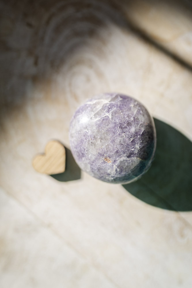 Lepidolit palmstone i lilla nuancer - kendt for beroligelse, følelsesmæssig balance og stresslindring.